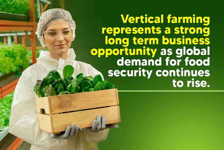 Worker holding harvested leafy greens inside an indoor vertical farming facility