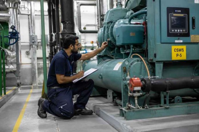 Outsourced Facility Management UAE technician inspecting industrial equipment Outsourced Facility Management UAE technician inspecting industrial equipment