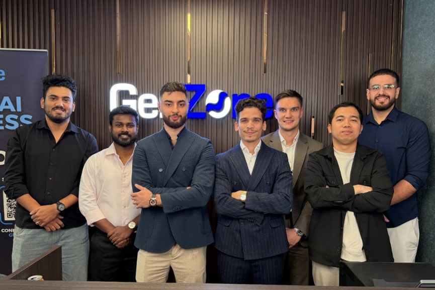 Seven GenZone team members posing in front of the company logo.